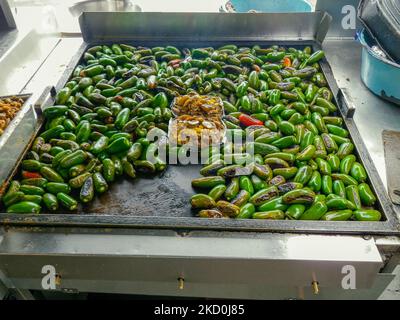 Jalapeno-Paprika, die auf einem großen, flachen Grill in Baja California, Mexiko geröstet werden. Stockfoto