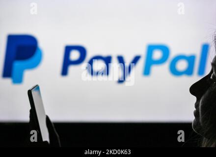 Ein Bild einer Frau, die ein Mobiltelefon vor das PayPal-Logo hält, das auf einem Computerbildschirm angezeigt wird. Am Dienstag, den 12. Januar 2021, Kanada. (Foto von Artur Widak/NurPhoto) Stockfoto