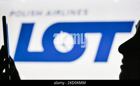 Ein Bild einer Frau, die ein Mobiltelefon vor dem LOGO VON LOT Polish Airlines hält, das auf einem Computerbildschirm angezeigt wird. Am Dienstag, den 12. Januar 2021, Kanada. (Foto von Artur Widak/NurPhoto) Stockfoto