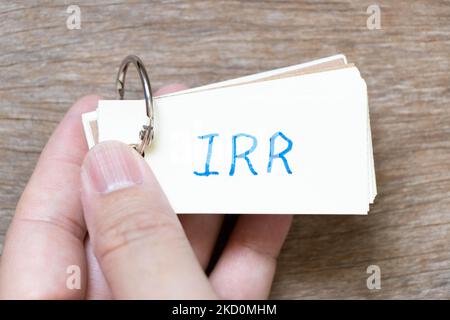 Hand hold flash card with handwriting in word IRR (Abbreviation of internal rate of return) on wood background Stockfoto