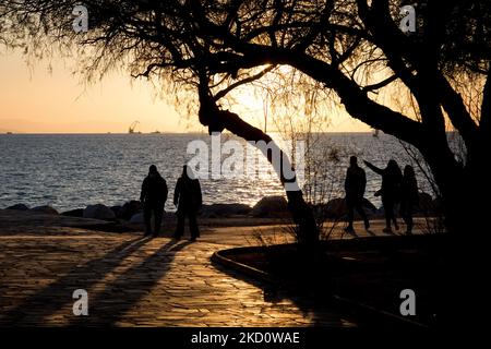 Einheimische und Touristen genießen den Sonnenuntergang, wenn sie den Tag am Strand der Flisvos Bay im Stadtteil Paleo Faliro in der Nähe von Athen, Griechenland, am 20. Januar 2022 verbringen. (Foto von Nikolas Kokovlis/NurPhoto) Stockfoto