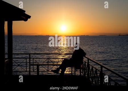 Einheimische und Touristen genießen den Sonnenuntergang, wenn sie den Tag am Strand der Flisvos Bay im Stadtteil Paleo Faliro in der Nähe von Athen, Griechenland, am 20. Januar 2022 verbringen. (Foto von Nikolas Kokovlis/NurPhoto) Stockfoto