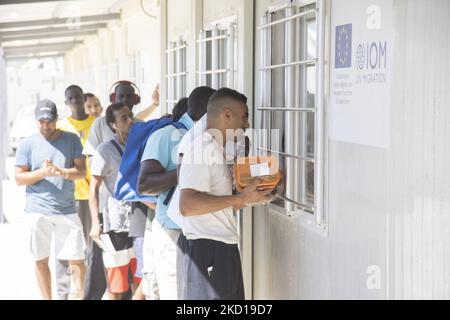 Die Leute warten in der Schlange, um die Verteilung der Mittagsgerichte zu erhalten. Innerhalb des neuen Flüchtlingslagers auf der Insel Samos, das mit Unterstützung der EU in Griechenland eingerichtet wurde, ist es die erste von der EU finanzierte geschlossene kontrollierte Einrichtung, das neue Samos RIC (Reception and Identification Center) Da Europa 276 Millionen Euro EU-Mittel für neue Camps auf den Inseln Samos, Lesbos, Chios, Kos und Leros ausgeben wird. Tägliches Leben im neuen Migrantenlager mit den Fertighäusern, einer geschlossenen kontrollierten Einrichtung, in die Menschen nur mit ihrer Karte zusätzlich zu ihrem biometrischen Fingerabdruck eintreten können. Das neue Lager Stockfoto