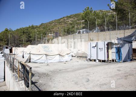 Weiße Zelte im offiziellen Lager mit dem Logo des UNHCR - DES UN-Flüchtlingshilfswerks. Das ehemalige offizielle Flüchtlingslager, das von Stacheldrahtzaun auf der Insel Vathy auf Samos umgeben ist, und das benachbarte provisorische Lager mit handgefertigten Zelten und einigen von UNHCR, das sich direkt neben den Häusern der Stadt Vathi befindet, wie es als verlassen gilt. Das Lager wurde geleert und die Leute wurden umgesiedelt oder mit der Polizeieskorte in das neue Lager und einige wenige Häuser verlegt. Einst beherbergte diese Einrichtung zu ihren Höchstzeiten 7500 Asylbewerber in den offiziellen Einrichtungen, aber auch das provisorische Lager im Wald, das den Spitznamen Jun erhielt Stockfoto