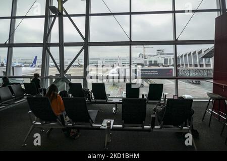 Blick auf ein Flugzeug und einen Passagier auf den verstellbaren Sitzen. Innerhalb des Brüsseler Flughafens BRU vor der COVID-Pandemie. Passagiere werden gesehen, wie sie am Hauptterminal, an der beweglichen Rolltreppe oder im zollfreien Bereich des Brüsseler Flughafens Zaventem laufen und an den Gates warten, um in das Flugzeug zu gelangen und in einem Flug abzufliegen, ohne soziale Distanzierung und Gesichtsmask, Die Realität vor der Coronavirus-Pandemie und die Sicherheitsmaßnahmen, die die Ausbreitung des COVID-19-Virus verhindern. Die Luftfahrtindustrie und der Personenverkehr stehen mit dem Covid-19 CO in einer schwierigen Phase Stockfoto