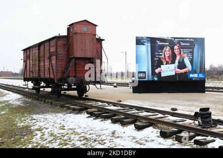 Am 27. Januar 2022 sind im ehemaligen KZ-Vernichtungslager Auschwitz II-Birkenau in Brzezinka bei Oswiecim, Polen, ein Original-Eisenbahnwagen für Deportationen und ein Bildschirm mit „Wir erinnern“-Videos des Jüdischen Weltkongresses zum 77.. Jahrestag der Befreiung von Auschwitz - Birkenau zu sehen. (Foto von Beata Zawrzel/NurPhoto) Stockfoto