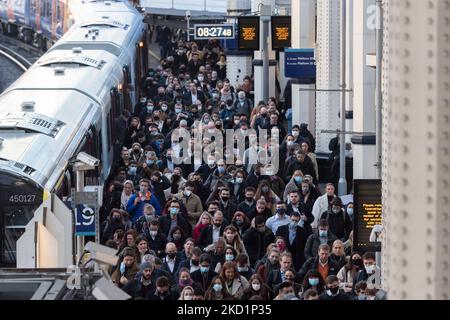 LONDON, GROSSBRITANNIEN - 02. FEBRUAR 2022: Pendler, einige davon tragen weiterhin Gesichtsmasken, kommen am 02. Februar 2022 während der morgendlichen Hauptverkehrszeit in London, England, am Bahnhof Waterloo an. Seit der Lockerung der Covid-19-Maßnahmen in der vergangenen Woche, als Arbeitnehmer und Käufer in die Innenstadt zurückkehren, ist die Zahl der Fahrgäste im gesamten Verkehrsnetz gestiegen. Gestern verzeichnete das Vereinigte Königreich 112.458 neue Fälle, da Reinfektionen erstmals in die offiziellen Statistiken aufgenommen wurden. (Foto von Wiktor Szymanowicz/NurPhoto) Stockfoto