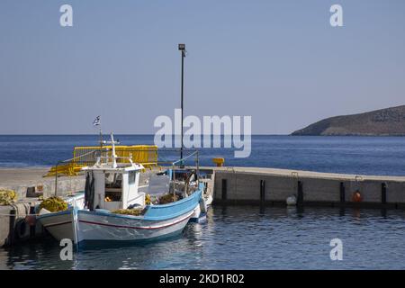 Ein traditionelles Fischerboot am Hafen. Szene des Hafens der Insel mit einigen kleinen Booten, die vor Anker liegen. Livadia, der Hafen und das Hauptdorf der Insel Tilos mit den weiß getünchten Häusern der traditionellen Architektur und dem Strand mit dem kristallklaren Meerwasser. Telos ist eine kleine griechische Mittelmeerinsel in der Ägäis, einem Teil der dodekanischen Inseln, mit 780 Einwohnern in der Nähe der türkischen Küste. Ende 2018 wurde Tilos die erste Insel im Mittelmeer, die ausschließlich mit Wind- und Solarenergie betrieben wurde, einer grünen autarken Insel, einer Initiative der EU für grüne Energie aus Stockfoto