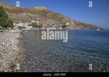 Der Kiesstrand von Livadia. Livadia, der Hafen und das Hauptdorf der Insel Tilos mit den weiß getünchten Häusern der traditionellen Architektur und dem Strand mit dem kristallklaren Meerwasser. Telos ist eine kleine griechische Mittelmeerinsel in der Ägäis, einem Teil der dodekanischen Inseln, mit 780 Einwohnern in der Nähe der türkischen Küste. Ende 2018 wurde Tilos die erste Insel im Mittelmeer, die ausschließlich mit Wind- und Solarenergie betrieben wurde, einer grünen autarken Insel, einer von der EU finanzierten Initiative für grüne Energie aus erneuerbaren Quellen zum Schutz der natürlichen Umwelt. Tilos Island, Gree Stockfoto