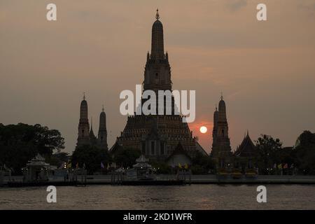 Die Sonne untergeht hinter dem Stupa des buddhistischen Tempels Wat Arun oder dem 'Tempel der Morgenröte', von der anderen Seite des Chao Phraya Flusses in Bangkok, Thailand, gesehen, 05. Februar 2022. (Foto von Anusak Laowias/NurPhoto) Stockfoto