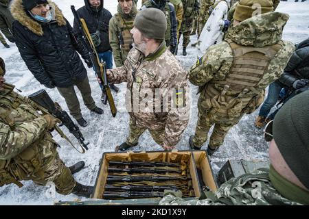 Ein Freiwilliger der Territorial Defense Brigade 112. in Kiew verteilt Gewehre während einer Militärübung für Zivilisten in den Außenbezirken der Stadt. Das Verteidigungsministerium schuf in den Hauptstädten Verteidigungsbrigaden, weil die hohe Spannung mit dem Aufbau russischer Truppen an seiner Grenze und die Gefahr einer Invasion durch Russland besteht. (Foto von Celestino Arce/NurPhoto) Stockfoto