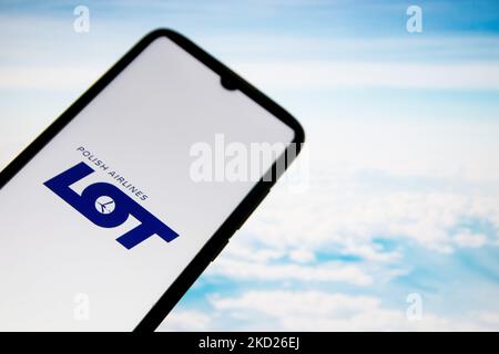 In dieser Abbildung ist eine MENGE Logo von Polish Airlines zu sehen, das auf einem Smartphone-Bildschirm mit einem Computertapete im Hintergrund in Athen, Griechenland, am 8. Februar 2022 angezeigt wird. (Fotoillustration von Nikolas Kokovlis/NurPhoto) Stockfoto