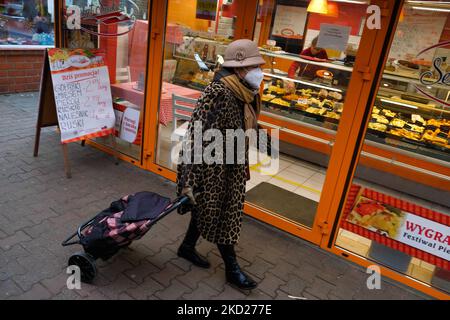 Eine Frau mit einer schützenden Gesichtsmaske geht am 8. Februar 2022 auf dem Marktplatz von Stary Kleparz in Krakau, Polen, spazieren. (Foto von Jakub Porzycki/NurPhoto) Stockfoto