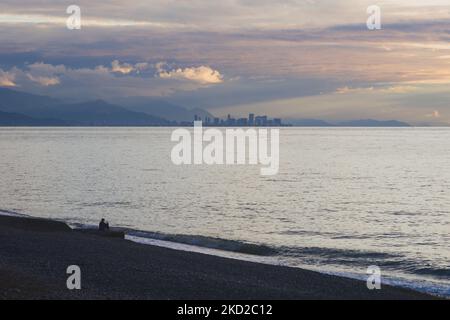 Ein einsamer Mann sitzt am Meer vor dem Hintergrund von Batumi, Georgia Stockfoto
