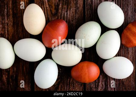 Blue, Green, and Brown Heritage Eggs auf einem rustikalen Holzhintergrund: Ansicht von oben auf einer Gruppe von einem Dutzend bunten Eiern auf einem Holztisch Stockfoto