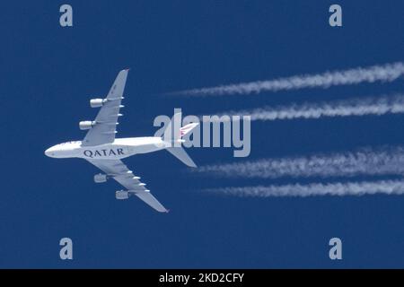 Qatar Airways Airbus A380-Doppeldecker überfliegt an einem sonnigen Tag über Europa 40,000 Meter am blauen Himmel und verbindet die Hauptstadt des Flughafens Katar Doha mit London Heathrow LHR in Großbritannien. A388 das überfliegende Großkörper-Düsenflugzeug hat den Aufdruck MIT DEM QATAR-Logo auf der Unterseite des Rumpfes und hinterlässt Kondensstreifen, eine weiße Dampflinie. Die A380 ist ein großes Großkörperflugzeug, das größte Passagierflugzeug der Welt. Das spezifische Quadjet-Doppeldeck hat die Registrierung A7-APH und wird von 4x EA Engine Alliance GP7200 Jet-Motor angetrieben Stockfoto