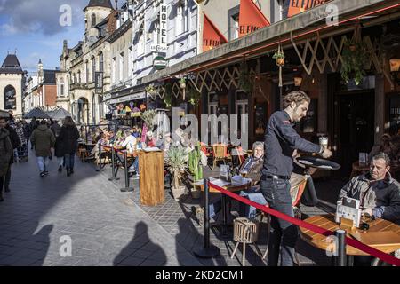 Das tägliche Leben in Valkenburg aan de Geul oder Valkenberg mit Menschen, die die Sonne auf den Terrassen der Cafés und Restaurants genießen, während die Geschäfte nach der Wintersperre wieder geöffnet werden, um die Coronavirus-Pandemie Covid-19 zu bekämpfen. Valkenburg ist eine historische niederländische Stadt in der Provinz Limburg mit dem Fluss Geul mit den berühmten Cafés, Bars, Tavernen und Restaurants, ein Reise- und Tourismusziel. Die Stadt war von den Überschwemmungen im Sommer 2021 nach dem extremen Wetter, starken Niederschlägen und hohen Wasserständen, die Evakuierungen zur Folge hatten, betroffen. Valkenburg, Niederlande am 5. Februar 2022 (Foto: Nicolas Economou Stockfoto