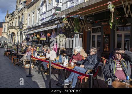 Das tägliche Leben in Valkenburg aan de Geul oder Valkenberg mit Menschen, die die Sonne auf den Terrassen der Cafés und Restaurants genießen, während die Geschäfte nach der Wintersperre wieder geöffnet werden, um die Coronavirus-Pandemie Covid-19 zu bekämpfen. Valkenburg ist eine historische niederländische Stadt in der Provinz Limburg mit dem Fluss Geul mit den berühmten Cafés, Bars, Tavernen und Restaurants, ein Reise- und Tourismusziel. Die Stadt war von den Überschwemmungen im Sommer 2021 nach dem extremen Wetter, starken Niederschlägen und hohen Wasserständen, die Evakuierungen zur Folge hatten, betroffen. Valkenburg, Niederlande am 5. Februar 2022 (Foto: Nicolas Economou Stockfoto