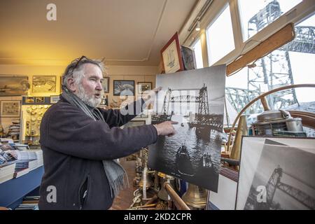 Der Ladenbesitzer eines Nautikladens in der Nähe der Brücke Klaas Jan Hoeve zeigt ein historisches, altes Schwarz-Weiß-Bild der Brücke, wobei die Brücke sichtbar war. Die ikonische historische De Hef - Koningshavenbrug Brücke in der niederländischen Hafenstadt Rotterdam kann für Jeff Bezos Superyacht abgebaut werden, um unterzugehen, da der Mast des Segelbootes die Höhe der Brücke überschreitet. Die zwei-Turm-Brücke mit Pendellift ist eine alte Stahleisenbahn-Brücke, die die Insel Noordereiland in der Maas im südlichen Teil von Rotterdam verbindet. Die Brücke wurde 1877 erbaut und erlitt im Jahr 1940 Schäden Stockfoto