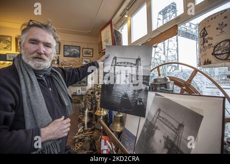 Der Ladenbesitzer eines Nautikladens in der Nähe der Brücke Klaas Jan Hoeve zeigt ein historisches, altes Schwarz-Weiß-Bild der Brücke, wobei die Brücke sichtbar war. Die ikonische historische De Hef - Koningshavenbrug Brücke in der niederländischen Hafenstadt Rotterdam kann für Jeff Bezos Superyacht abgebaut werden, um unterzugehen, da der Mast des Segelbootes die Höhe der Brücke überschreitet. Die zwei-Turm-Brücke mit Pendellift ist eine alte Stahleisenbahn-Brücke, die die Insel Noordereiland in der Maas im südlichen Teil von Rotterdam verbindet. Die Brücke wurde 1877 erbaut und erlitt im Jahr 1940 Schäden Stockfoto