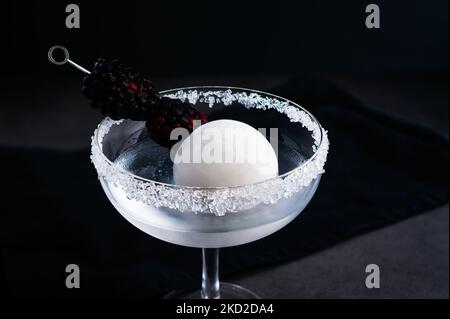 Full Moon Martini mit Blackberry-Garnierung Closeup: Wodka-Cocktail mit opaker weißer Eiskugel und Fruchtgarnitur Stockfoto