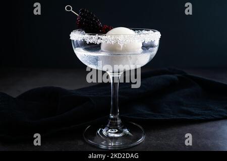 Full Moon Martini mit Blackberry-Garnierung: Wodka-Cocktail mit opaker weißer Eiskugel und Fruchtgarnitur Stockfoto