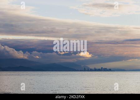 Panorama einer modernen Stadt in der Ferne vor dem Hintergrund des Meeres, der Berge, der Sonnenuntergangszeit. Batumi, Georgia Stockfoto