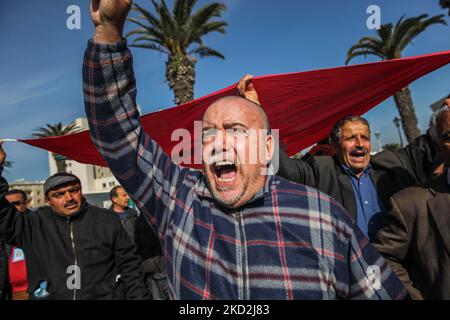 Ein Anhänger der islamistisch inspirierten Partei Ennahda ruft Slogans aus, während Demonstranten am 13. Februar 2022 auf Initiative der Kampagne „Bürger gegen den Putsch – die Demokratische Initiative“ auf der Mohamed 5 Avenue in der tunesischen Hauptstadt Tunis eine riesige tunesische Flagge erheben. Um gegen die Auflösung des Obersten Justizrats des Landes zu protestieren und die Unabhängigkeit der Justiz zu fordern. Die Demonstranten forderten auch die Freilassung des Vizepräsidenten der Ennahda-Partei Noureddine Bhiri, der seit mehr als sechs Wochen unter Hausarrest gestellt wird. Auch Demonstranten Stockfoto