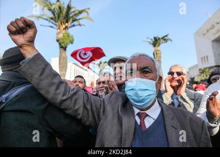 Ein Anhänger der islamistisch inspirierten Partei Ennahda hebt die Faust, während ein weiterer die tunesische Flagge schwenkt, während einer Demonstration auf Initiative der Kampagne „Bürger gegen den Putsch – die Demokratische Initiative“ am 13. Februar 2022 in der Mohamed 5 Avenue in der Hauptstadt Tunis, Tunesien, Um gegen die Auflösung des Obersten Justizrats des Landes zu protestieren und die Unabhängigkeit der Justiz zu fordern. Die Demonstranten forderten auch die Freilassung des Vizepräsidenten der Ennahda-Partei Noureddine Bhiri, der seit mehr als sechs Wochen unter Hausarrest gestellt wird. Demonstranten auch proteste Stockfoto