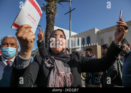 Eine Unterstützerin der islamistisch inspirierten Partei Ennahda wirft am 13. Februar 2022 auf der Mohamed 5 Avenue in der tunesischen Hauptstadt Tunis eine Kopie der tunesischen Verfassung vor, die auf Initiative der Kampagne „Bürger gegen den Putsch – die Demokratische Initiative“ stattfand. Um gegen die Auflösung des Obersten Justizrats des Landes zu protestieren und die Unabhängigkeit der Justiz zu fordern. Die Demonstranten forderten auch die Freilassung des Vizepräsidenten der Ennahda-Partei Noureddine Bhiri, der seit mehr als sechs Wochen unter Hausarrest gestellt wird. Demonstranten protestierten auch gegen Agai Stockfoto