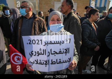 Eine Unterstützerin der islamistisch inspirierten Partei Ennahda hält ein Plakat mit der Aufschrift auf Arabisch „17. Dezember 2021, die revolutionäre Explosion, um den Putsch zu stürzen“ während einer Demonstration, die auf Initiative der Kampagne „Bürger gegen den Putsch – die Demokratische Initiative“ stattfand, Auf der Mohamed 5 Avenue in der tunesischen Hauptstadt Tunis am 13. Februar 2022, um gegen die Auflösung des Obersten Justizrats des Landes zu protestieren und die Unabhängigkeit der Justiz zu fordern. Die Demonstranten forderten auch die Freilassung des Vizepräsidenten der Ennahda-Partei Noureddine Bhiri, der unter hous gestellt wird Stockfoto