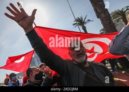 Ein Anhänger der islamistisch inspirierten Partei Ennahda hebt seinen Arm neben einer riesigen tunesischen Flagge während einer Demonstration auf Initiative der Kampagne „Bürger gegen den Putsch – die Demokratische Initiative“ am 13. Februar 2022 in der Mohamed 5 Avenue in der Hauptstadt Tunis, Tunesien, Um gegen die Auflösung des Obersten Justizrats des Landes zu protestieren und die Unabhängigkeit der Justiz zu fordern. Die Demonstranten forderten auch die Freilassung des Vizepräsidenten der Ennahda-Partei Noureddine Bhiri, der seit mehr als sechs Wochen unter Hausarrest gestellt wird. Demonstranten protestierten auch gegen Agai Stockfoto