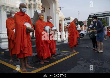 Thailändische buddhistische Mönche, die Schutzmasken tragen, erhalten während der Almosenzeremonie, die den buddhistischen Makha Bucha-Tag in Bangkok, Thailand, am 16. Februar 2022, feiert, Opfergaben von Anhängern. (Foto von Anusak Laowias/NurPhoto) Stockfoto