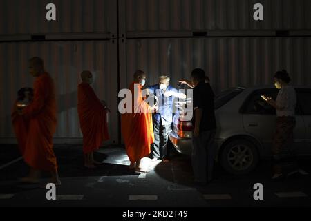 Thailändische buddhistische Mönche, die Schutzmasken tragen, erhalten während der Almosenzeremonie, die den buddhistischen Makha Bucha-Tag in Bangkok, Thailand, am 16. Februar 2022, feiert, Opfergaben von Anhängern. (Foto von Anusak Laowias/NurPhoto) Stockfoto