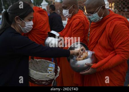 Thailändische buddhistische Mönche, die Schutzmasken tragen, erhalten während der Almosenzeremonie, die den buddhistischen Makha Bucha-Tag in Bangkok, Thailand, am 16. Februar 2022, feiert, Opfergaben von Anhängern. (Foto von Anusak Laowias/NurPhoto) Stockfoto