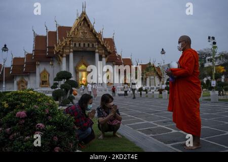 Thailändische buddhistische Mönche, die Schutzmasken tragen, erhalten während der Almosenzeremonie, die den buddhistischen Makha Bucha-Tag in Bangkok, Thailand, am 16. Februar 2022, feiert, Opfergaben von Anhängern. (Foto von Anusak Laowias/NurPhoto) Stockfoto