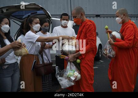 Thailändische buddhistische Mönche, die Schutzmasken tragen, erhalten während der Almosenzeremonie, die den buddhistischen Makha Bucha-Tag in Bangkok, Thailand, am 16. Februar 2022, feiert, Opfergaben von Anhängern. (Foto von Anusak Laowias/NurPhoto) Stockfoto