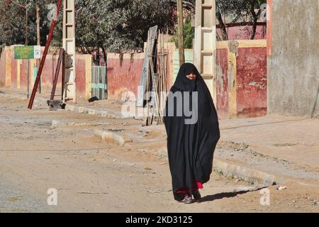 Frau (die einen traditionellen schwarzen „Haik“-Körpermantel trägt), die in einem abgelegenen Wüstendorf tief im Hohen Atlas in Marokko, Afrika, auf einer Straße unterwegs ist. (Foto von Creative Touch Imaging Ltd./NurPhoto) Stockfoto