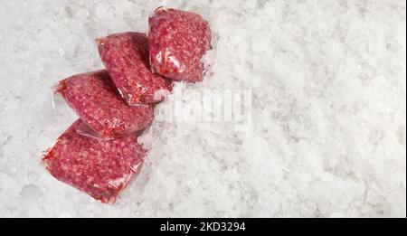 Fleischpasteten aus Rindfleisch in Staubsaugerbeuteln auf Eis auf weißem Hintergrund - Panorama Stockfoto