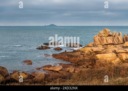 Frankreich, Ploumenach, 2022-01-13. Ein Mann fischt am Ende einer Felsformation entlang der rosafarbenen Granitküste in der Bretagne. Foto von Alexander BEE Stockfoto
