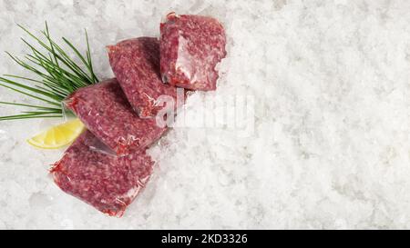 Fleischpasteten aus Rindfleisch in Staubsaugerbeuteln auf Eis auf weißem Hintergrund - Panorama Stockfoto