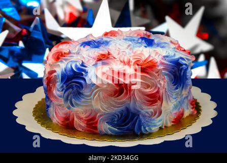 Nahaufnahme eines Weihnachtskuchens mit cremigem, zuckerhaltigen roten Weiß- und blauen Tüpfelchen auf einem goldenen Papier vor dunklem Hintergrund Stockfoto