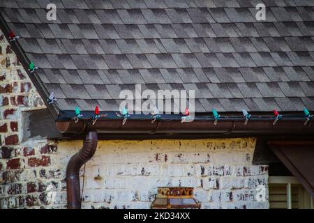 Nahaufnahme der Kupferrinnen des Backsteinhauses mit Bildschirm und montierten roten und grünen Weihnachtsdekorationsleuchten Stockfoto