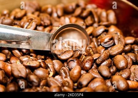 Kaffee nach Maß - Kaffeebohnen im Kontanier mit Messlöffel - selektiver Fokus Stockfoto