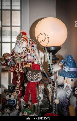 Sammlung von Weihnachtsfiguren wie asiatischer weihnachtsmann und Fischeule sowie Zauberer und Nussknacker auf dem Eingangstisch mit Blick auf die französische Tür Stockfoto