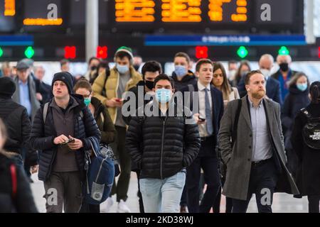 LONDON, GROSSBRITANNIEN - 22. FEBRUAR 2022: Pendler, einige davon tragen weiterhin Gesichtsmasken, kommen während der morgendlichen Hauptverkehrszeit am Bahnhof Waterloo an, da alle verbleibenden Covid-Beschränkungen Englands am 22. Februar 2022 in London, England, Ende dieser Woche enden werden. Gestern kündigte der britische Premierminister Boris Johnson die langfristige Strategie der Regierung für das Leben mit Covid-19 in England an, einschließlich der Aufhebung der gesetzlichen Verpflichtung zur Selbstisolierung nach Tests, die ab Donnerstag diese Woche positiv auf das Virus getestet wurden, sowie eines Endes der universellen freien Tests am 1.. April. (Foto von Wiktor Szymano Stockfoto