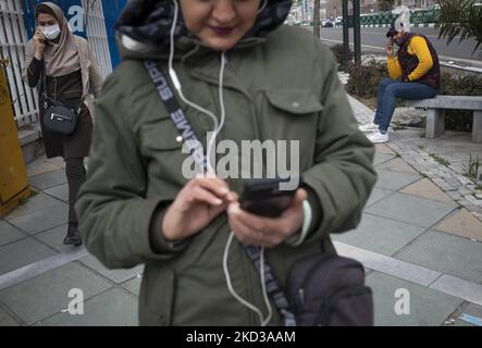 Eine iranische Frau und ein Mann sprechen auf ihren Telefonen, während eine Frau am 23. Februar 2022 ihre sozialen Medien auf einer Straße im Norden Teherans mit ihrem Smartphone überprüft. Mehrere Abgeordnete betonten in einer öffentlichen Sitzung am 23. Februar, dass der Plan zur Organisation von Cyberspace-Diensten nicht für die Blockierung des virtuellen Raums ist, während nach ISNA, Mitglieder der kommission für den Schutz der Nutzerrechte im Cyberspace haben in der heutigen Sitzung der kommission mit 18 Stimmen dem Gesetz zugestimmt. (Foto von Morteza Nikoubazl/NurPhoto) Stockfoto