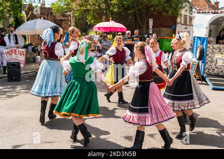 Bulgarische Volkstänzer in traditionellen Kostümen tanzen auf der Straße bei einer Veranstaltung in der englischen mittelalterlichen Stadt Sandwich im Sommer. Stockfoto