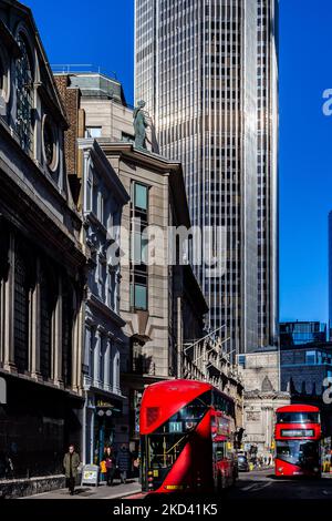 Zwei rote Londoner Routmaster-Busse fahren aneinander vorbei und das riesige und ikonische NWB-Gebäude überragt die Szene.Tageslicht beleuchtet das Gebäude Stockfoto