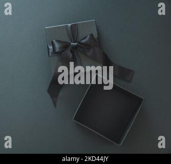 Black Friday Verkaufskonzept, Geschenkbox offen mit Schleife vor schwarzem Hintergrund, Draufsicht, Vorlage. Stockfoto